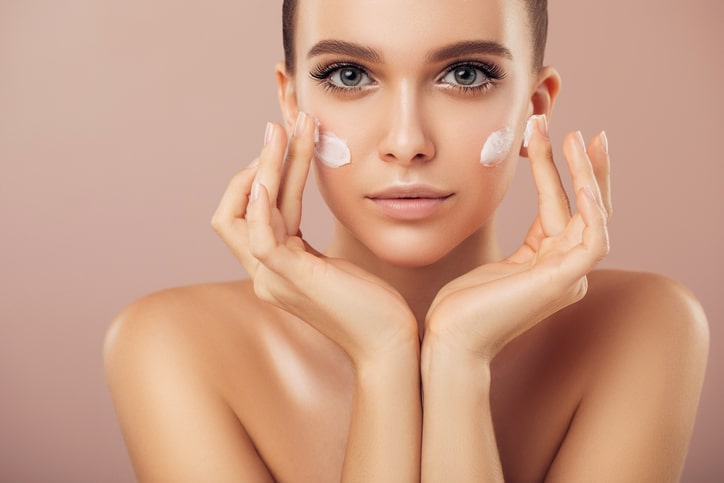 Woman applying magnesium lotion to face