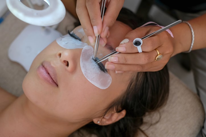 woman getting eyelash extensions applied