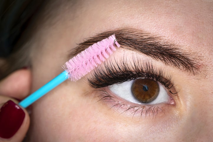 Woman Brushing Long Lasting Eyelash Extensions