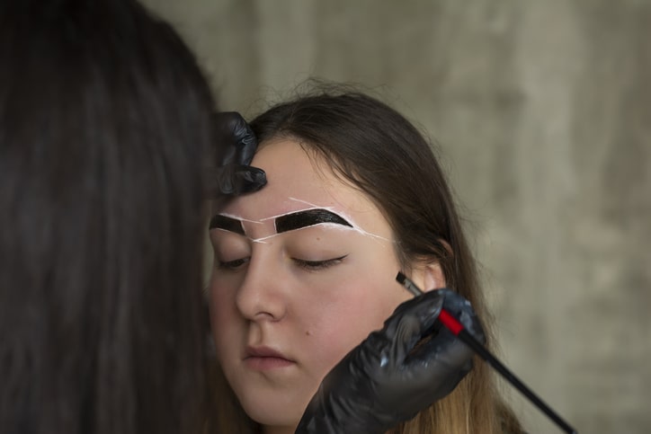 Woman getting eyebrows tinted at salon